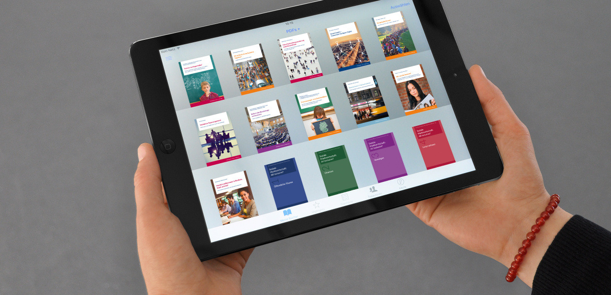 (© Bertelsmann Stiftung) Eine Frau hält ein Tablet in ihren Händen, auf dem die Titel mehrerer Bücher aus dem Verlag Bertelsmann Stiftung zu sehen sind.