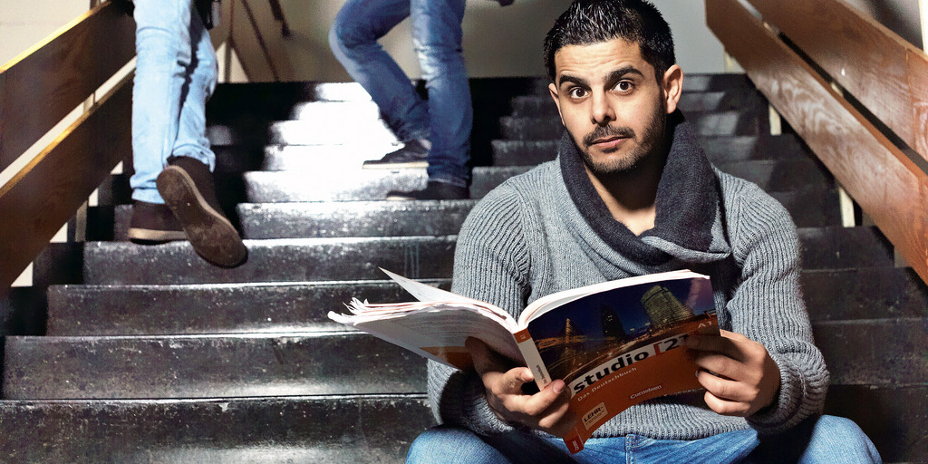 Ein Student sitzt im Treppenhaus der FU Berlin und hält ein Buch in den Händen.