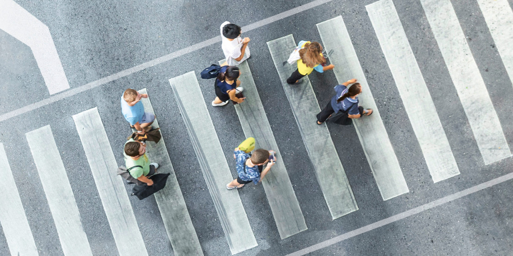 People crossing a street at a cross-walk, viewed from above.
