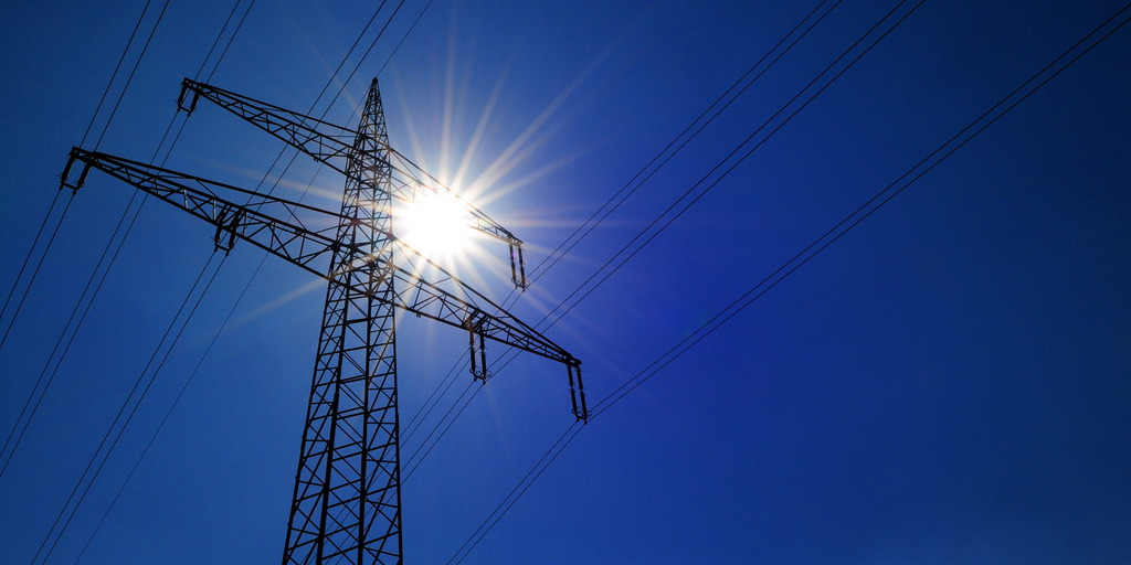 Hochspannungsleitung vor dunkelblauem Himmel mit Sonne