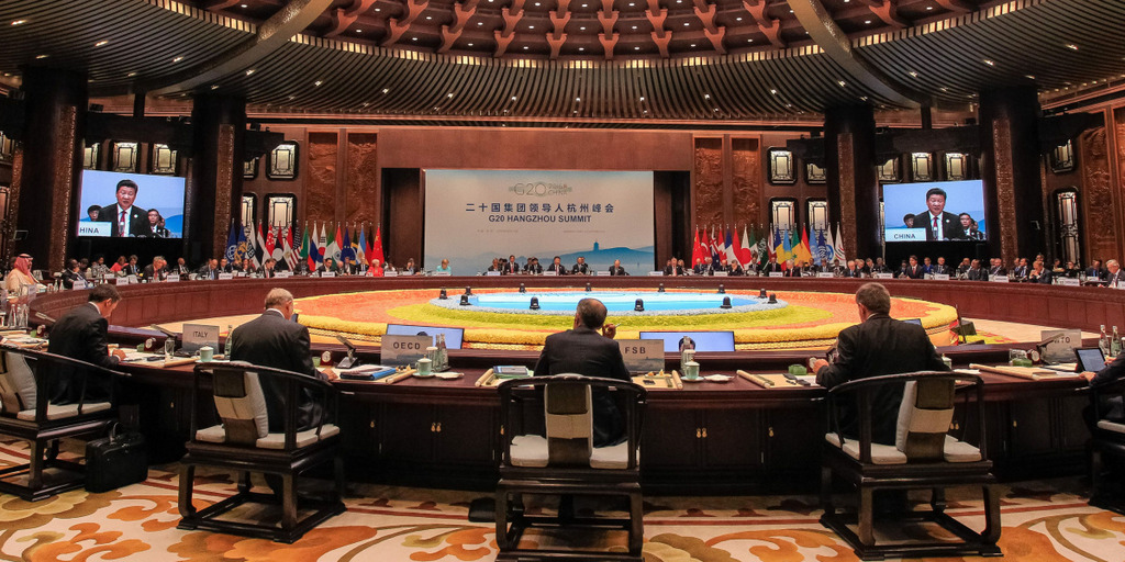 Blick in einen Konferenzraum des G20-Gipfels im chinesischen Hangzhou. Um einen runden Tisch versammelt sitzen Vertreter der G20 und hören einer Rede zu.