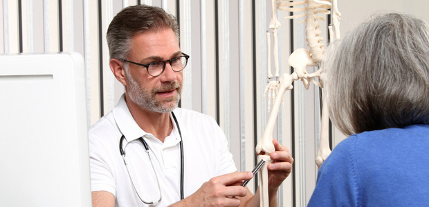 Arzt zeigt Patientin die Funktionsweise des Kniegelenks.
