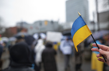 eine kleine Ukrainefahne wird in einer Hand festgehalten.