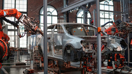 A gray vehicle being repaired by robotic machines in a factory. This photo is used in a policy brief "How buy-European rules can help save Europe's car industry," in cooperation with the following project partners: the Centre for European Reform and the Jacques Delors Centre.
