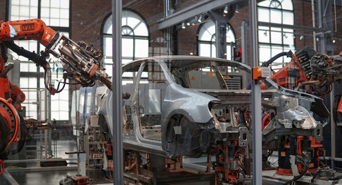 grey car being repaired by a robot in a hall