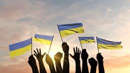 Silhouette von erhobenen Armen, die die ukrainische Flagge schwenken