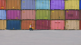 Engineer man with yellow crash helmet and worker west checking cargo freights in front of colorful cargo contrainer stacks in shipping port