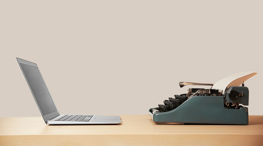 Ein Laptop und eine Schreibmaschine stehen sich gegenüber.