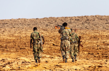 Back view of three Ethiopian soldiers walking in the wasteland.
