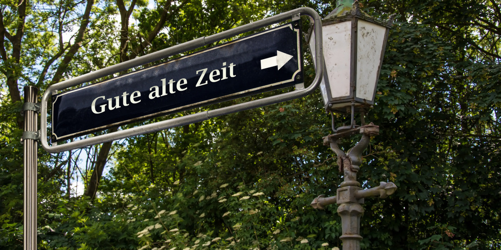 Zu sehen ist ein Straßenschild, auf dem 'gute alte Zeit' steht und eine alte Straßenlaterne.