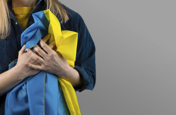 Woman holds ukrainian blue and yellow flag on black background