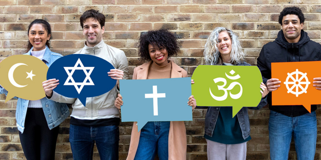 Fünf Personen halten lächelnd Schilder vor sich, die die Symbole des Islam, des Judentums, des Christentums, des Hinduismus und des Buddismus tragen.