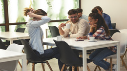 Drei junge Menschen sitzen an einem Tisch