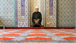 Ein betender Mann knienend auf einem Teppich.