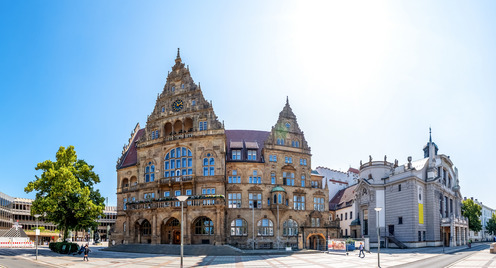 Ansicht des Bielefelder Rathauses sowie des Bielefelder Theaters mit strahlend, blauem Himmel.