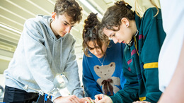 Junge Menschen beugen sich über einen Tisch