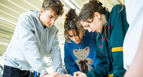 Junge Menschen beugen sich über einen Tisch