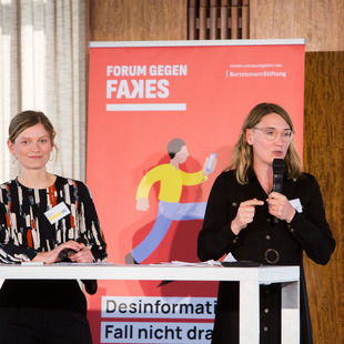 Zwei Damen vor einem Banner auf der Bühne