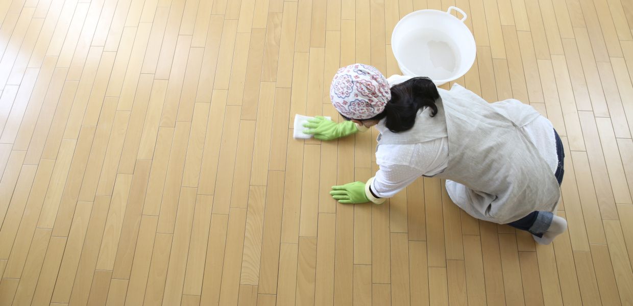 (© Shutterstock / kazoka) Eine Putzfrau wischt auf den Knien alleine einen großen Pakett-Fußboden