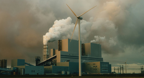 Windkraftrad mit Industrie im Hintergrund