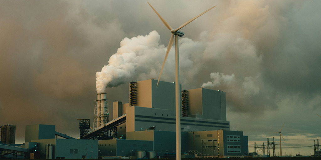 Windkraftrad mit Industrie im Hintergrund