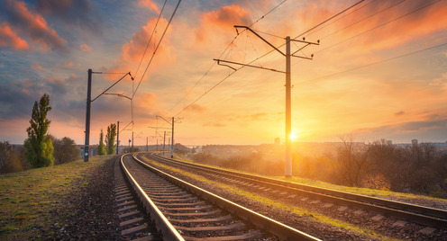 Bahnhof vor wunderschönem Himmel bei Sonnenuntergang. Industrielandschaft mit Eisenbahn, farbenfrohem blauem Himmel mit roten Wolken, Sonne, Bäumen und grünem Gras. Eisenbahnknotenpunkt. Schwerindustrie. Abend im Herbst.