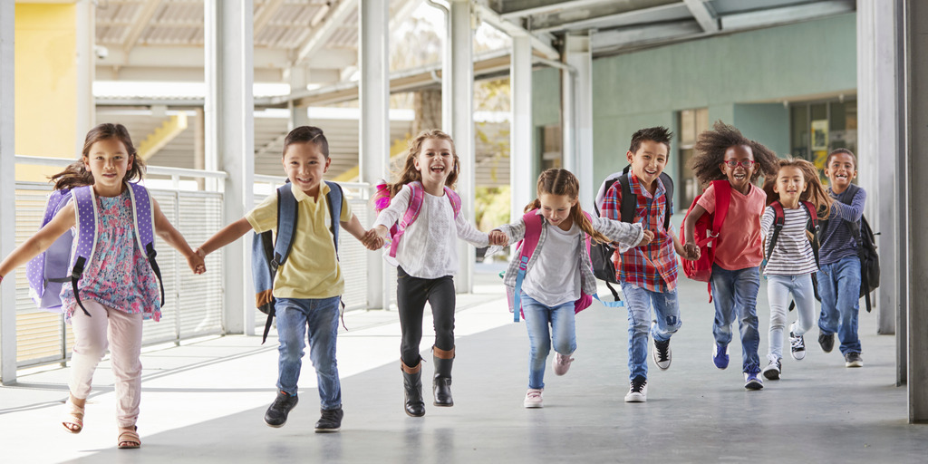 Grundschulkinder rennen händchenhaltend durch den Korridor.