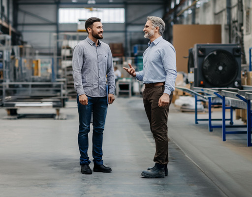 Zwei Arbeiter unterhalten sich in einer Lagerhalle.