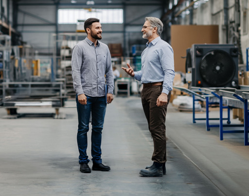 Zwei Arbeiter unterhalten sich in einer Lagerhalle.