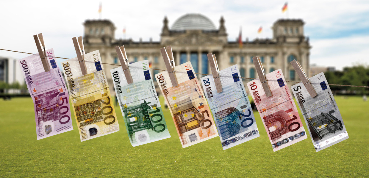 (© Creativ Studio Heinemann/Westend61/Getty Images) Geldscheine hängen an einer Wäscheleine vor dem deutschen Reichstag.