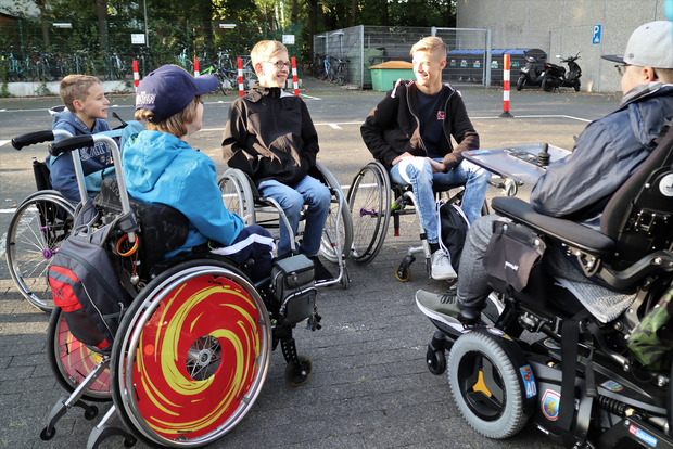 Mehre Schüler im Rollstuhl bilden einen Kreis auf dem Schulhof.