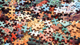 Many colorful puzzle pieces lie jumbled up on a surface