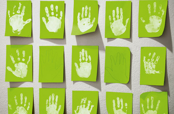 weiße Kinderhände auf grünen Pappen