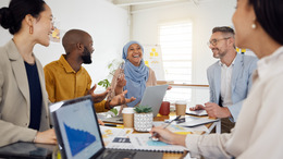 unterschiedliche Menschen sitzen zusammen an einem Besprechungstisch