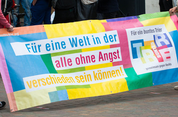 Zwei Personen halten ein buntes Banner in der Hand.
