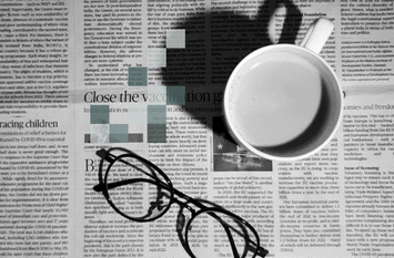 Aufgeschlagene Zeitung zu sehen und auf ihr steht eine Tasse mit Kaffee und eine Brille