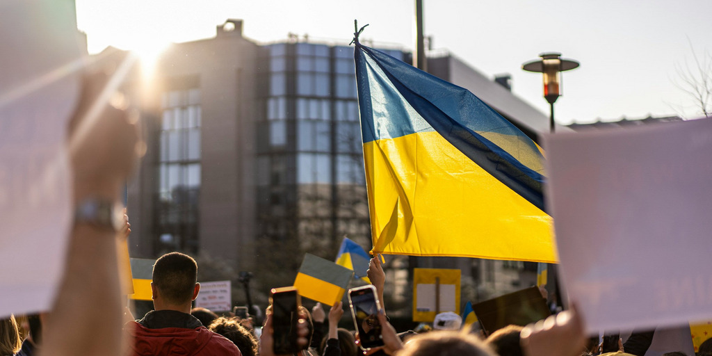 Menschen bei einer Demontration halten die Ukraine-Flagge hoch