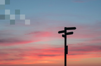 Himmel mit Sonnenuntergangsfarben zu sehen und um Vordergrund ein Schild mit vier verschiedenen Richtungen