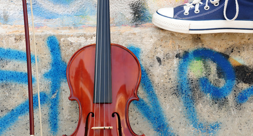 eine Geige steht vor einer Graffitiwand - Turnschuh am oberen Bildrand