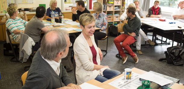 Lehrer sitzen in Gruppen an Schreibtischen und diskutierenLehrer sitzen in Gruppen an Schreibtischen und diskutierenLehrer sitzen in Gruppen an Schreibtischen und diskutieren