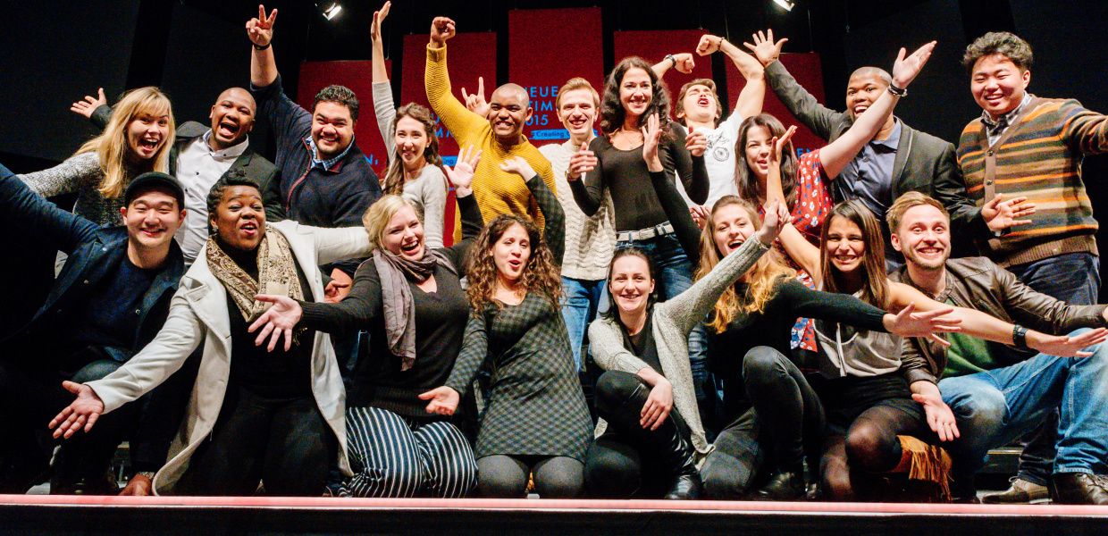 (© Besim Mazhiqi) The semifinalists of NEUE STIMMEN in the year 2015 kneel or stand on a stage and celebrate that they were selected for the semifinal.