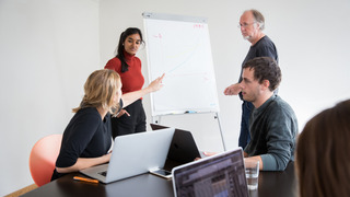 Vier Personen diskutieren vor einem Flipchart