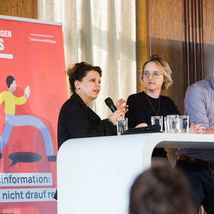 Drei Personen sprechen auf der Bühne