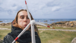 A girl blows on a scaled down windmill