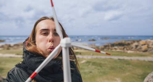 A girl blows on a scaled down windmill