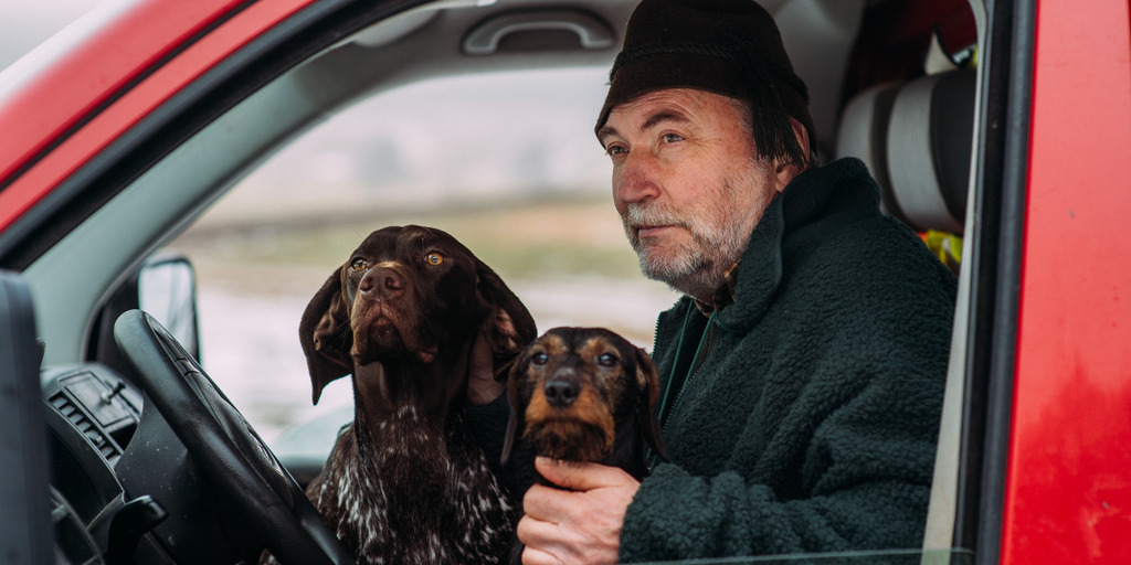 Heiner Sindel blickt aus dem geöffneten Fenster seines Autos. Er hat zwei Hunde auf seinem Schoß sitzen.