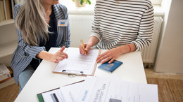 zwei Personen sitzen an Formularen an einem Tisch