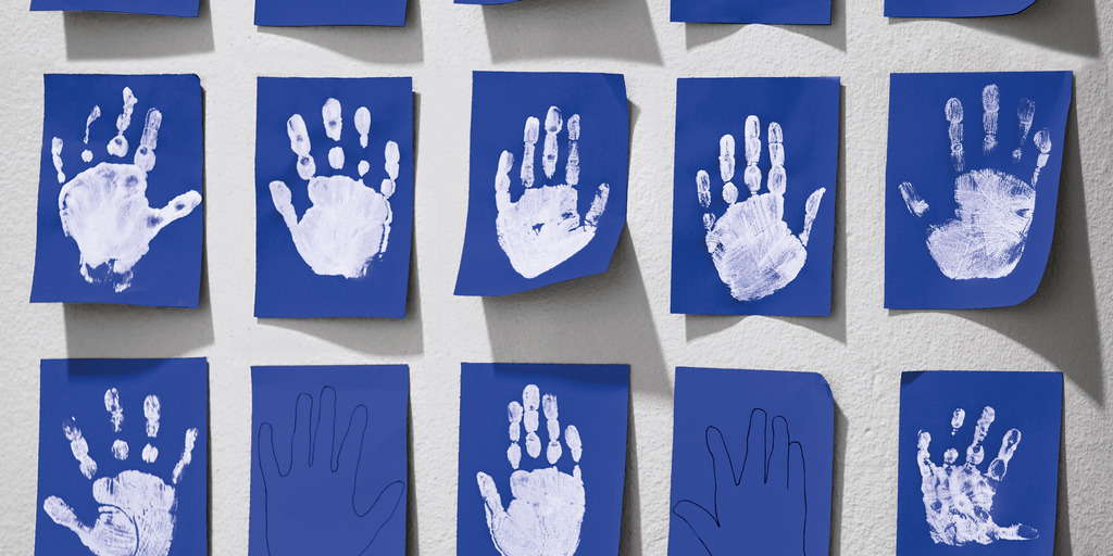 Blaues Papier mit weißen Handabdrücken von Kindern.