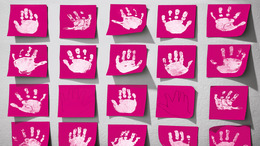 An einer wand sind rote Klebezettel befestigt. Auf einigen dieser Zettel sieht man Handabdrücke.