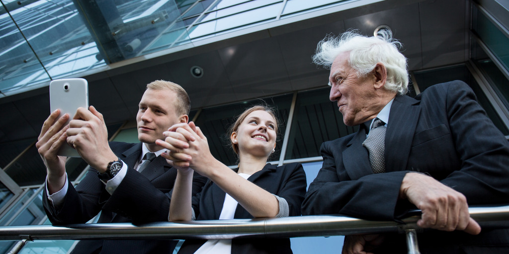 Three businessmen, a young woman, a young man and an older man talking on the observation balcony of a corporate building.